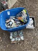 overview of tote with mixed electrical supplies, separate boxes of metal boxes and bulbs visible