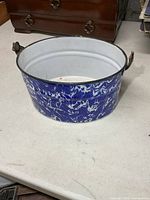 Side view of round blue white marbled enamelware bucket showing exterior finish