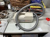 Hoover Sprint 100 canister vacuum with hose and attachments on table