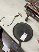 Ice tongs, clamp and griddle grouped on table