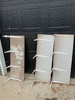 Three shelf boards with brackets leaning against garage door