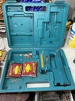 Open teal case containing Makita stapler and two staple boxes