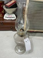 Full view of clear glass oil lamp showing base, burner, and chimney