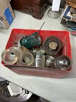 Red bin containing assorted glass insulators, some on wood pins