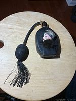 Full view of black glass atomizer bottle with bulb and tassel