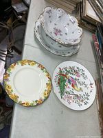 Group shot of all five pieces: three floral bowls, Royal Doulton plate, bird plate