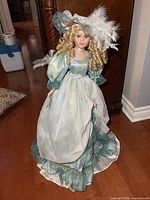 Full view of doll standing, displaying dress and hat