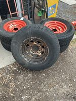 Five 6-bolt trailer tires stacked, red and rusty steel rims visible