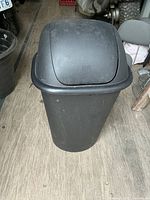 Full view of black plastic swing-lid trash can