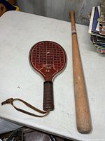 Full view of wooden baseball bat and paddle on table