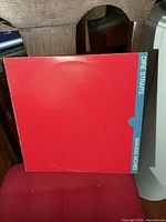 Front view of red album jacket with blue spine band