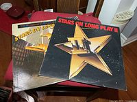 Front covers of Stars On Long Play I and II LPs on chair