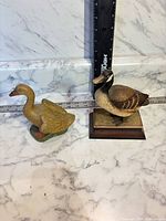 Front view of both duck figurines with ruler for scale