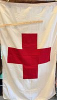 Full view of white flag with red cross and ruler for scale