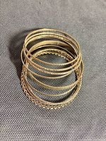 Nine silver-tone bangles stacked showing textures