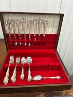 Open chest showing knives in lid, stacks of forks and spoons in base