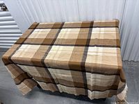 Full view of plaid wool throw blanket draped over table