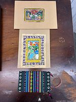 Overview of both folk art prints and woven pouch on table