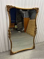 Full view of large gilt wood mirror leaning against wall