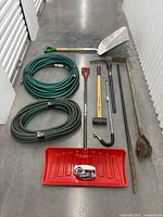All items laid out including shovels, hoses, long-handled tools and cultivator