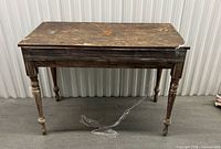 Front view of distressed solid wood table with turned legs