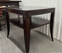 Three-quarter view showing table legs, shelf, overall form, and finish wear