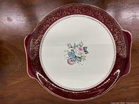 Front of porcelain platter showing floral center, burgundy rim, gold trim, and handles