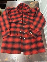 Front view of red and black buffalo check wool jacket showing snap buttons and pockets
