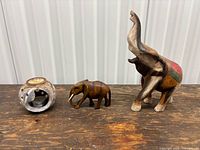 Group shot showing all three items: painted wooden elephant, small wooden elephant, ceramic tealight holder