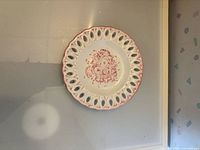 Front view of white ceramic plate with pink floral design and reticulated rim