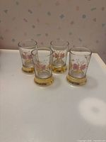 Front view of all four hand-painted floral shot glasses showing design and gold bases