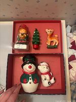 Overview of five wax holiday candles in two boxes