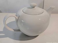 Side view of complete teapot showing body, spout, handle and lid