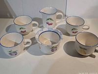 Full six-piece ceramic set laid out—four mugs, creamer, lidded sugar bowl