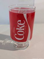 Full view of glass showing Enjoy Coke logo and pedestal base