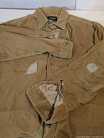 Full view of tan corduroy shirt jacket showing front, chest pockets, repairs