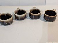 Four ceramic handled bowls in a row, showing exterior glaze and handles