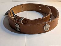 Full view of belt coiled showing buckle, Tweety stud, leather tone