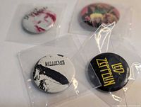 Front view showing all four buttons in individual plastic sleeves