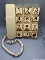 Front view showing handset, oversized 12-key touch-tone pad, coiled cord