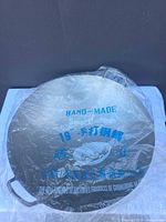 Wok in plastic wrap showing printed 'Hand-Made Steel Cauldron 19"' text