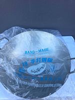 Full view of 19-inch handmade carbon steel wok in plastic wrap