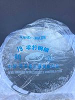 Wok in original plastic with 19" and hand-made markings visible