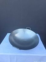 Front view of large carbon steel wok on table
