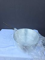 Pan wrapped in plastic showing long handle and helper handle