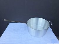 Side view of brushed aluminum saucepan showing long handle and helper handle