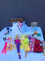 Overview of dolls, clothing, furniture, props on table