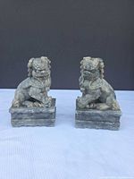 Front view of both carved stone guardian lions on plinths
