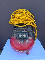 Front view of Porter-Cable red pancake compressor with coiled yellow hose