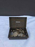 Open metal money box filled with assorted coins